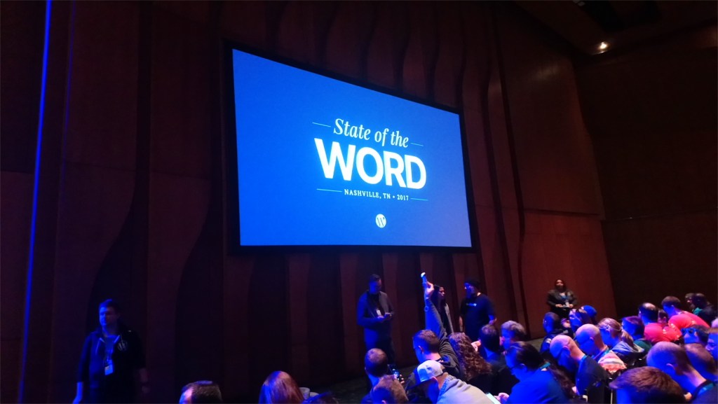Projector screen with "State of the Word" on the screen in a large conference hall before the presentation