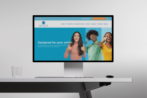 Website homepage of Ashby Park Family Orthodontics featuring the tagline 'Designed for your smile!' with three smiling young people giving thumbs up against colourful backgrounds.
