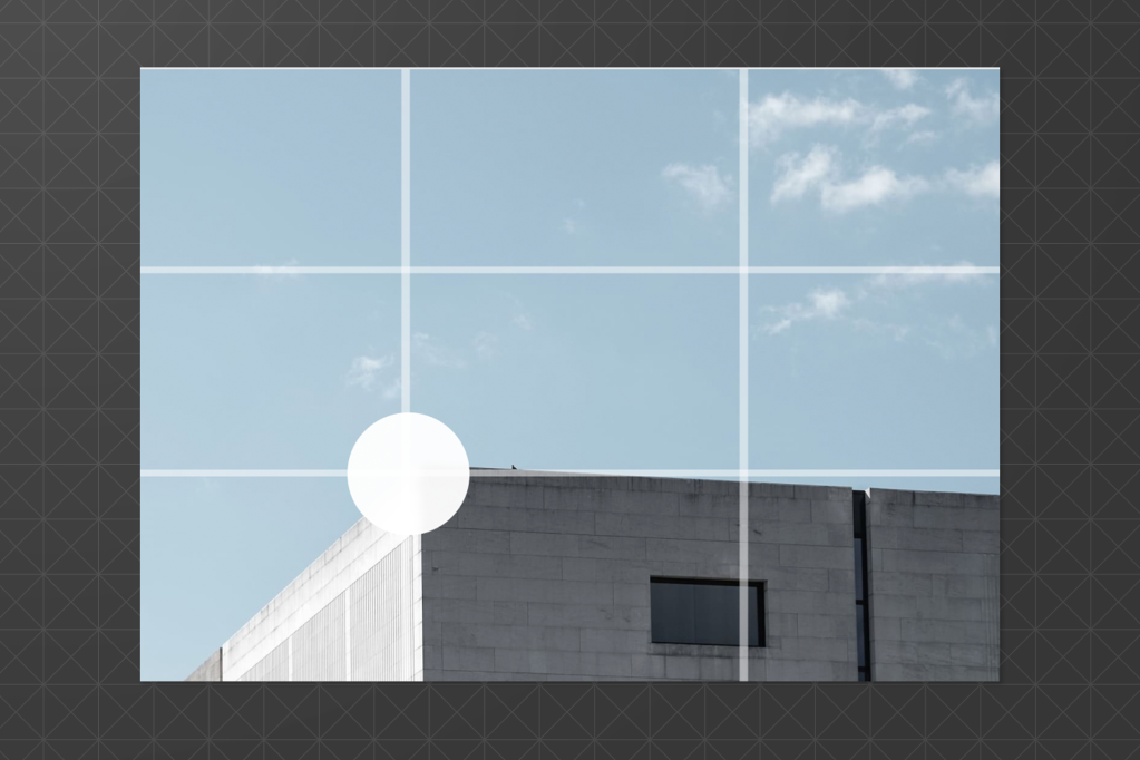 Cropping tool interface applied to a photo of a modern building under a blue sky, with a grid overlay and a circular focal point selector on the bottom-left area of the image.