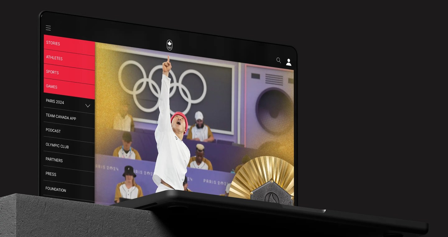 Olympic.ca site on tablet showing Paris 2024 athlete with raised arm and Olympic rings in background.