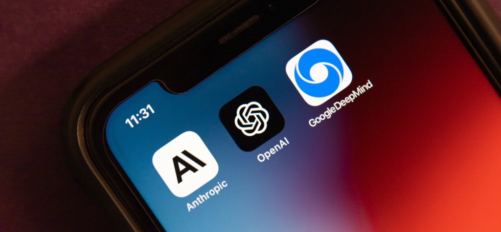 Close-up of a smartphone screen showing app icons for Anthropic, OpenAI, and Google DeepMind. The phone clock reads 11:31, and the background is a deep red gradient.