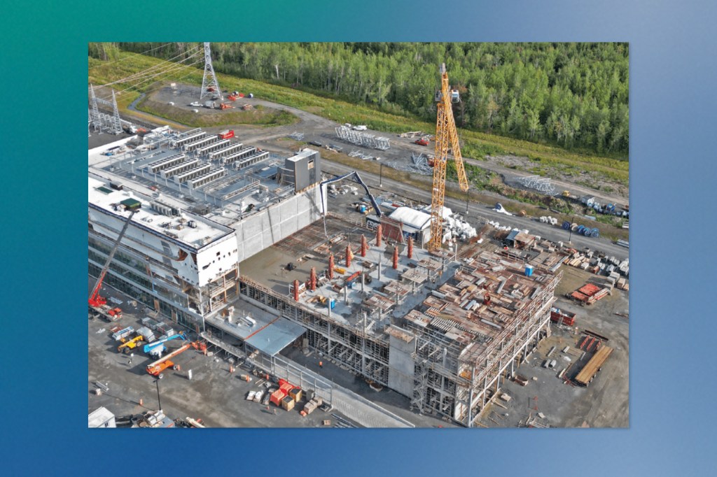 Aerial view of a large data center under construction in a forested area.