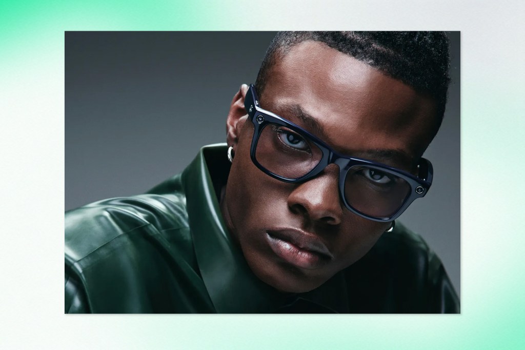 Portrait of a man wearing black-framed Ray-Ban Meta smart glasses, dressed in a dark green shirt, looking directly into the camera.