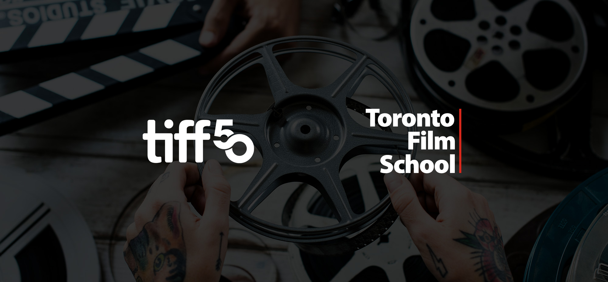 A close-up image of tattooed hands holding a film reel, overlaid with the TIFF 50 and Toronto Film School logos. The background includes other film reels and a partially visible film clapperboard, creating a cinematic and professional atmosphere.