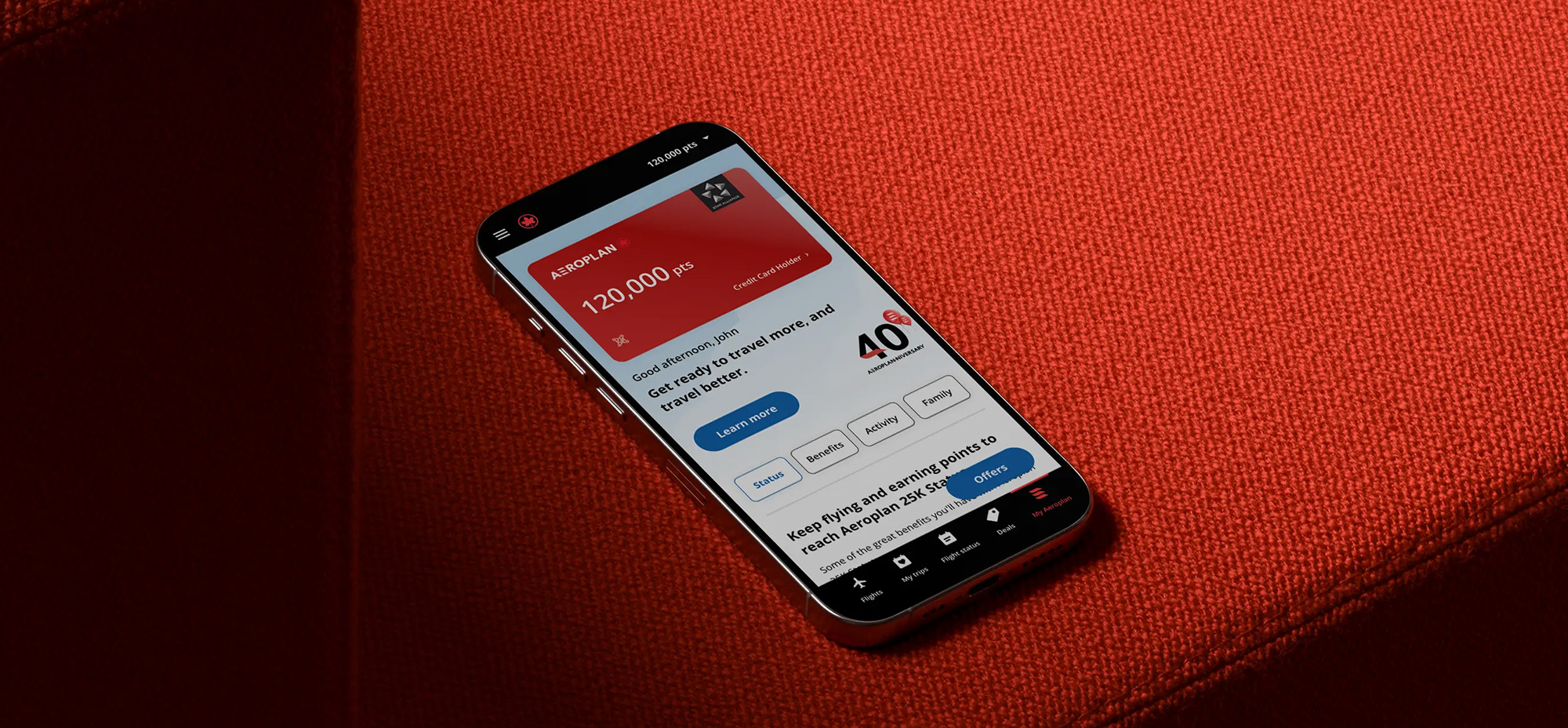 Smartphone resting on a red surface displaying the Aeroplan app with points balance and personalized travel options visible on screen.