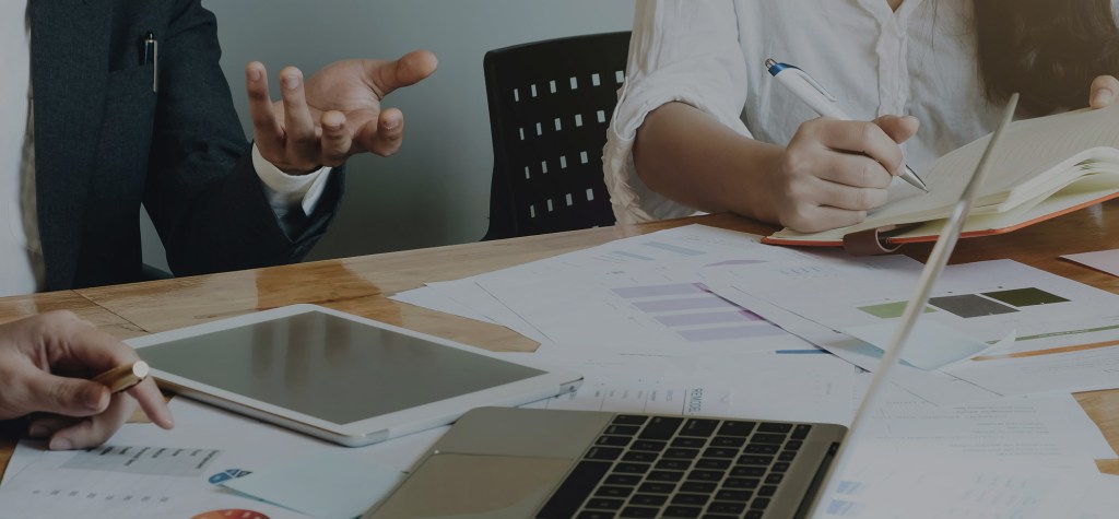 Enterprise stakeholders reviewing platform strategy documents and analytics reports across laptop, tablet, and printed materials, illustrating long-term architecture planning and collaborative decision-making.