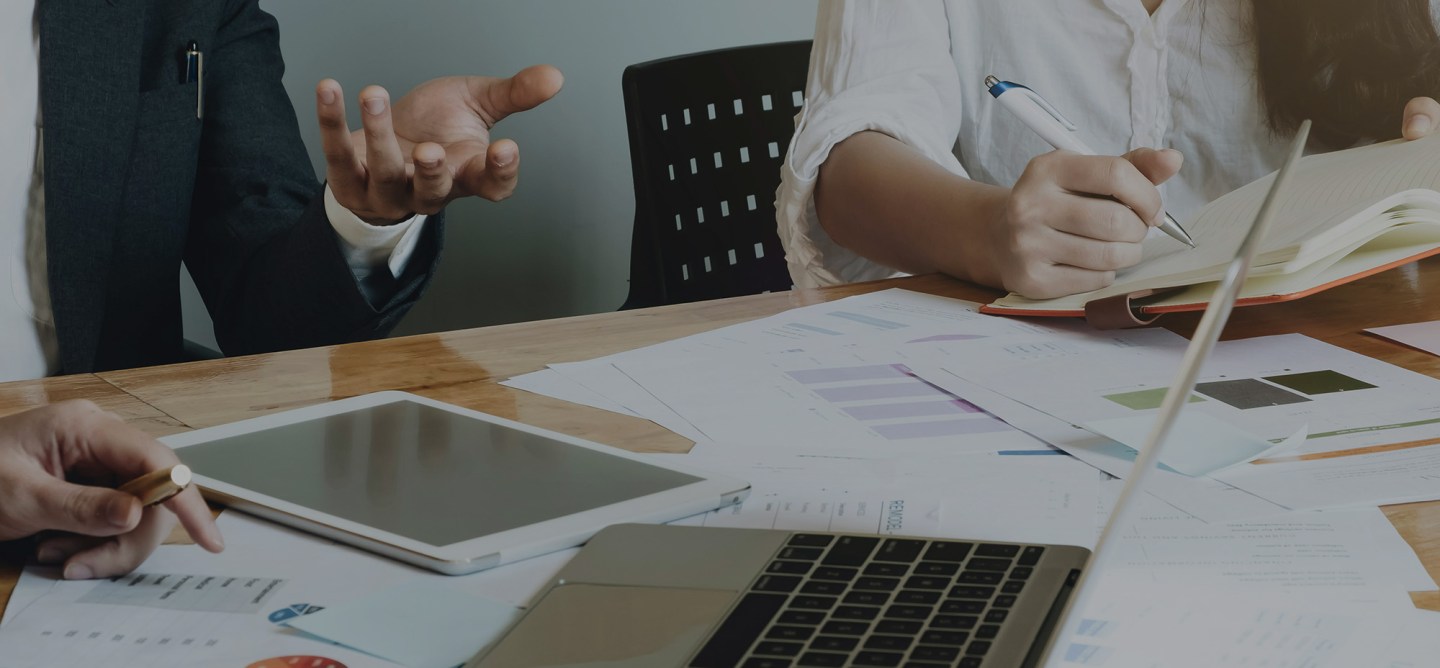 Enterprise stakeholders reviewing platform strategy documents and analytics reports across laptop, tablet, and printed materials, illustrating long-term architecture planning and collaborative decision-making.