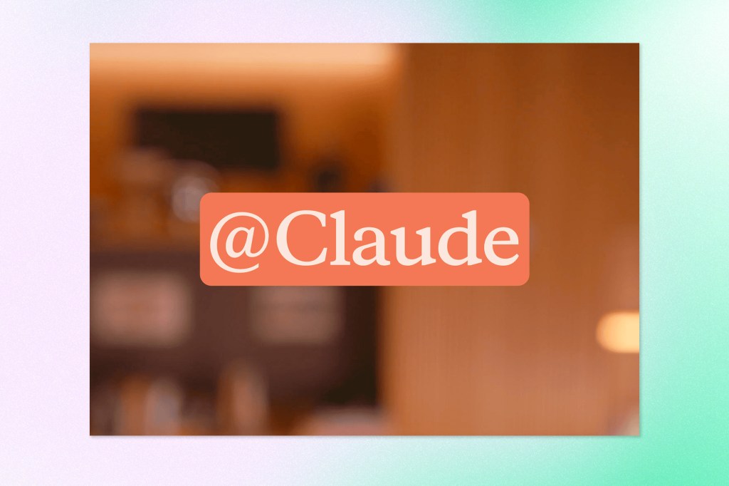 Blurred office background with an "@Claude" tag displayed prominently, representing Anthropic's Claude assistant in collaborative workplace conversations.