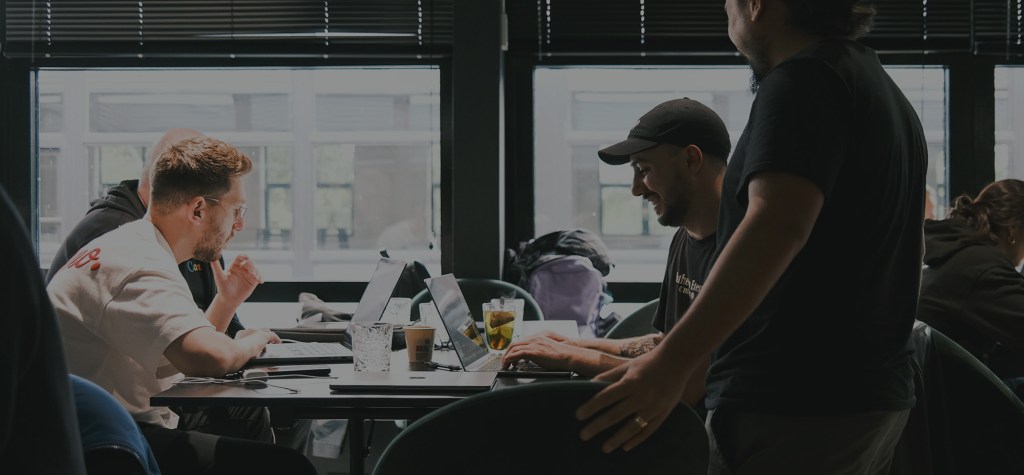 Group of professionals working on laptops around a shared table in a bright office.