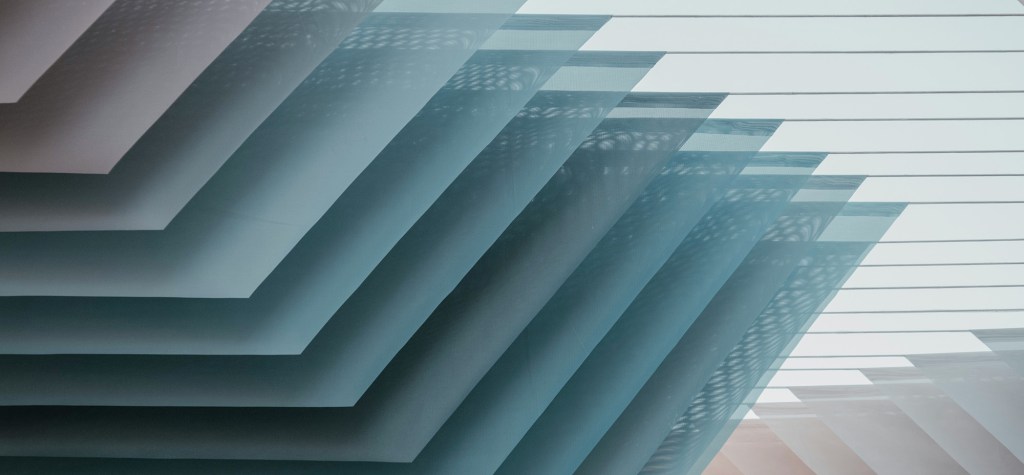 Abstract architectural view of layered horizontal building elements with repeating geometric lines and soft natural light, representing composable architecture, modular systems, and scalable digital platforms.
