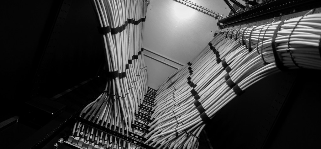 Black-and-white close-up of bundled network cables organized inside a server or telecommunications rack.