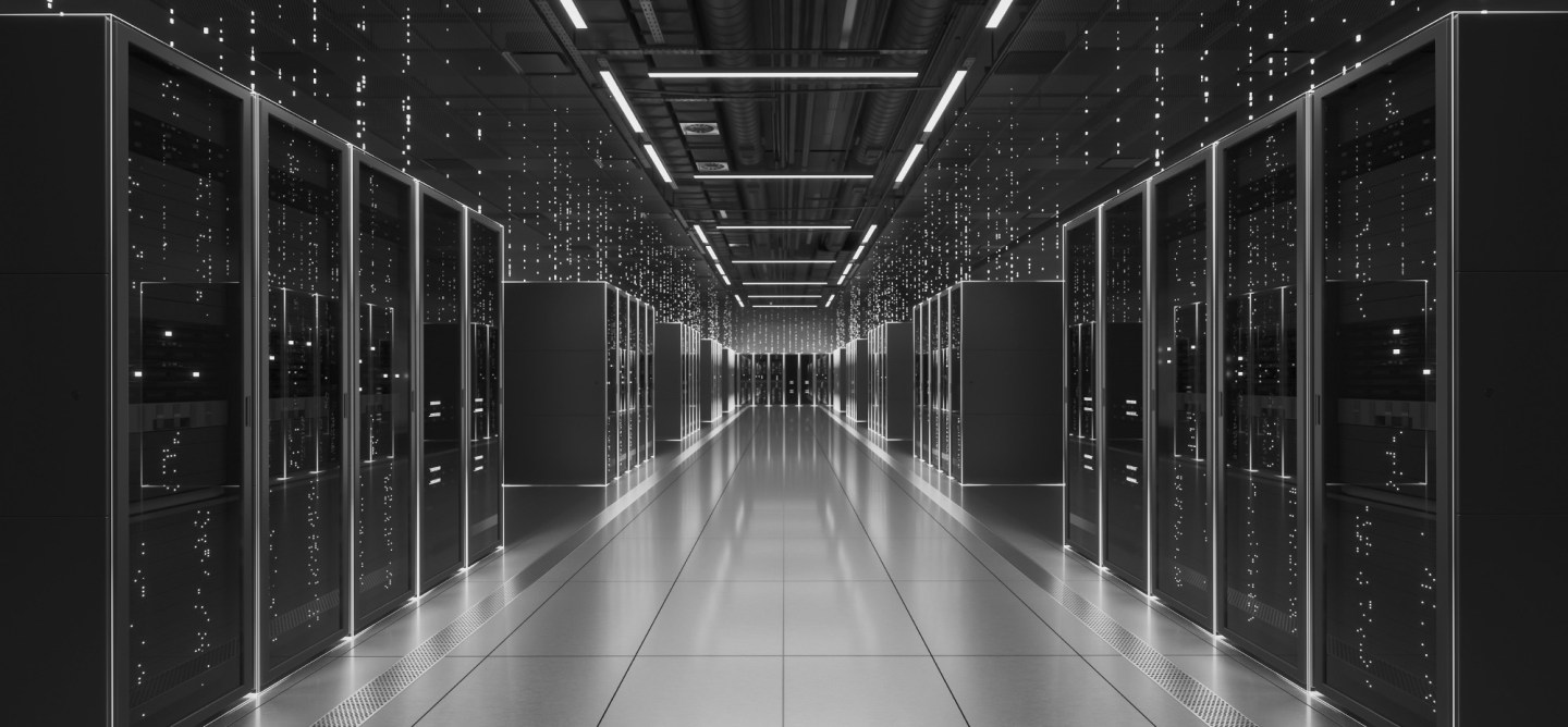 Black-and-white view of a modern data centre with rows of server racks lining a central aisle.