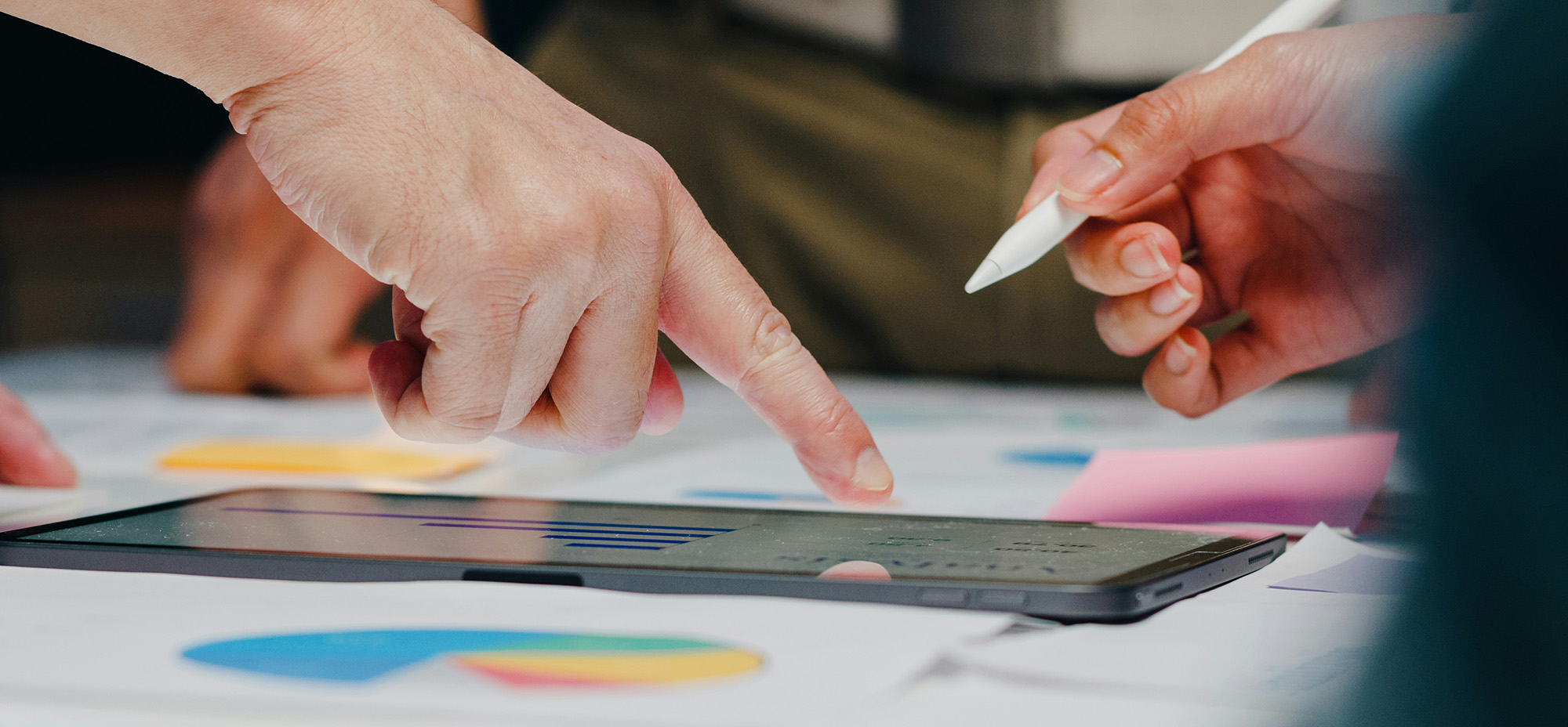 Two people reviewing data on a tablet, with one pointing at the screen while the other holds a stylus.